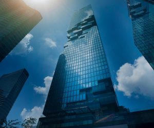 Tall glass skyscraper under sunny blue sky.