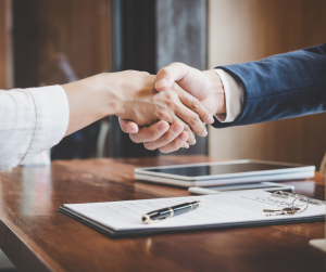 Business handshake over a contract on desk.