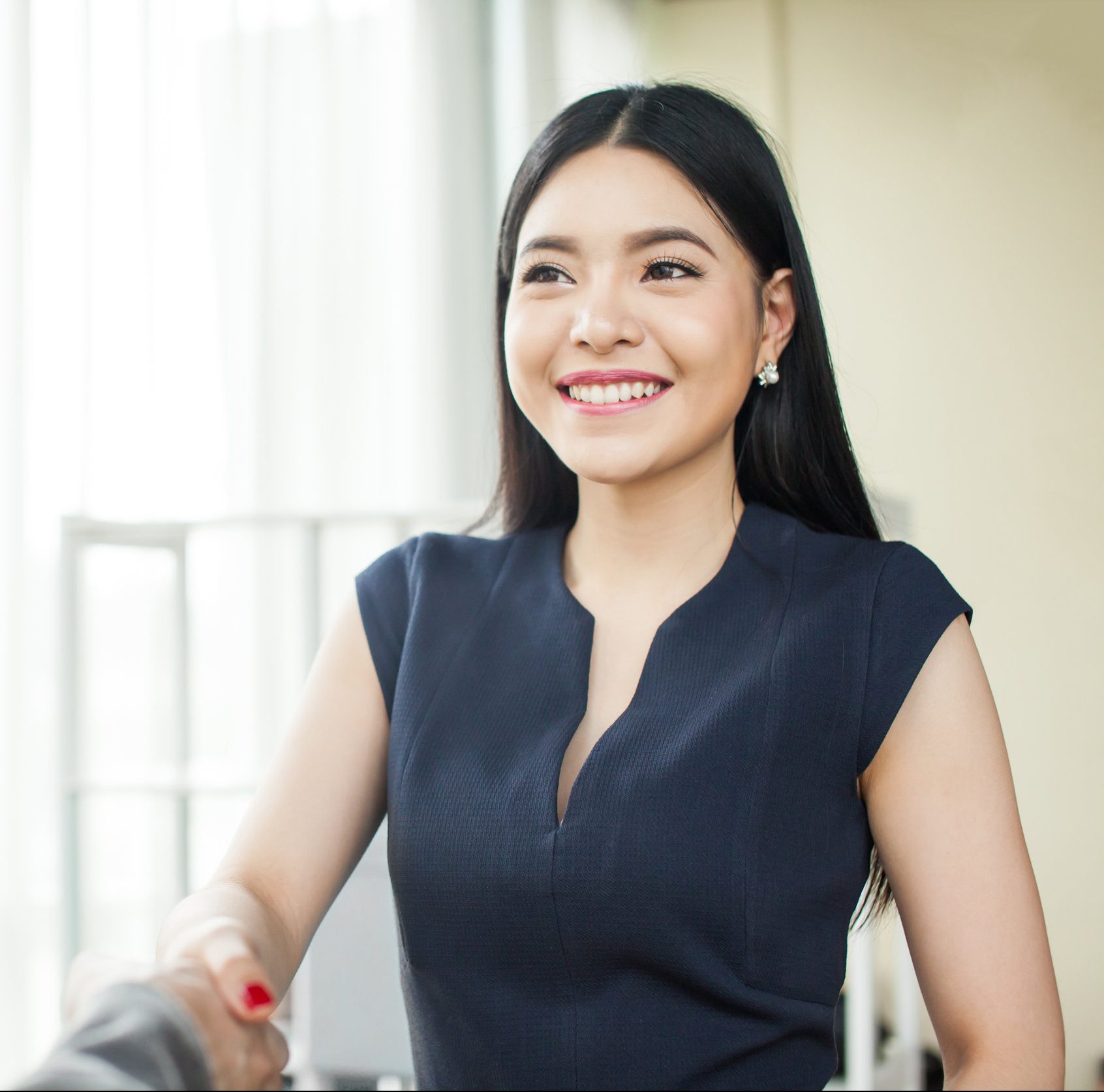 Smiling businesswoman extending hand for handshake.