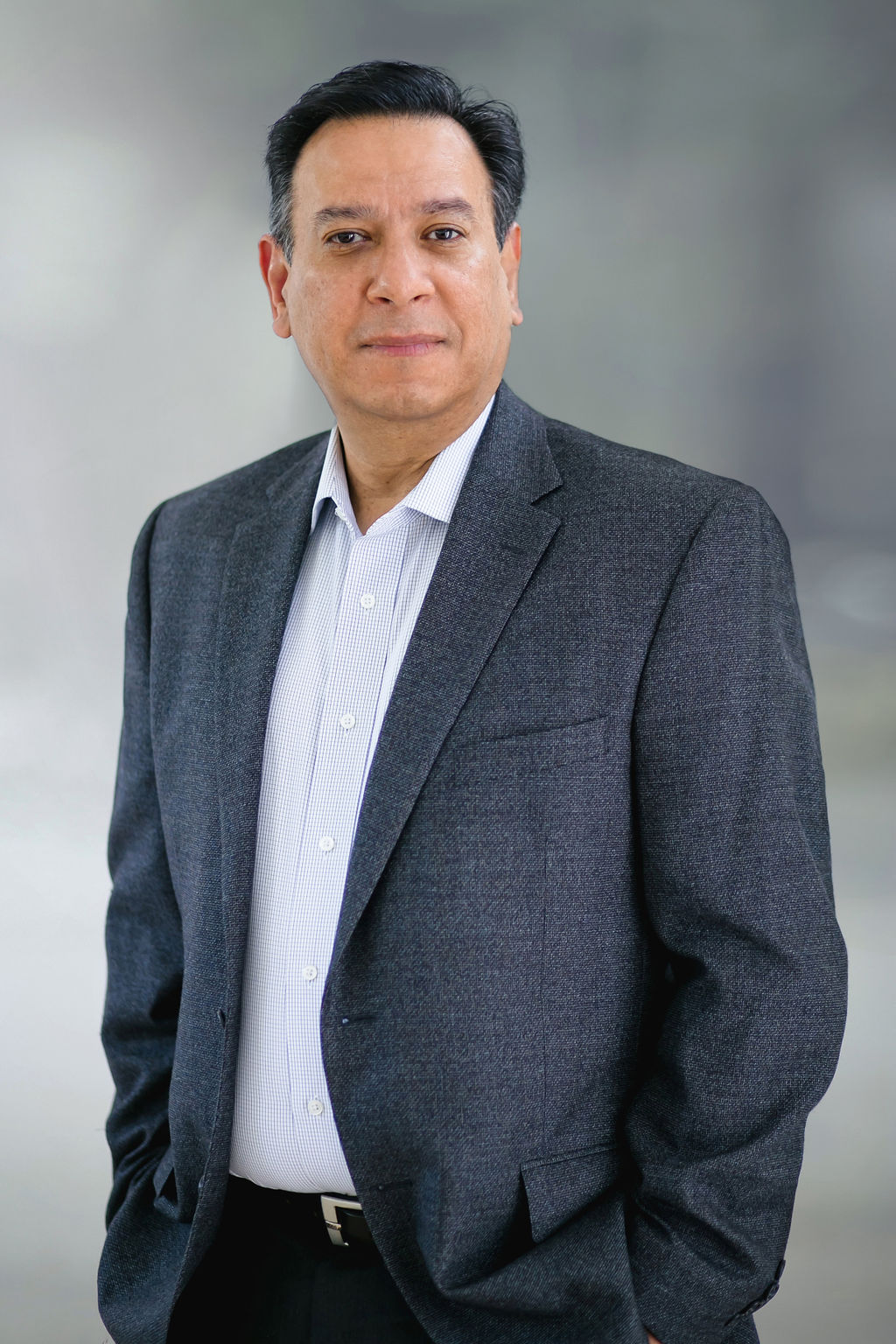 Professional man in business attire with neutral background.