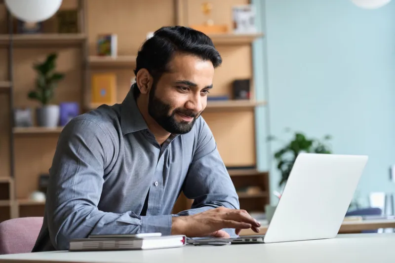 Man working contently on laptop in office setting.