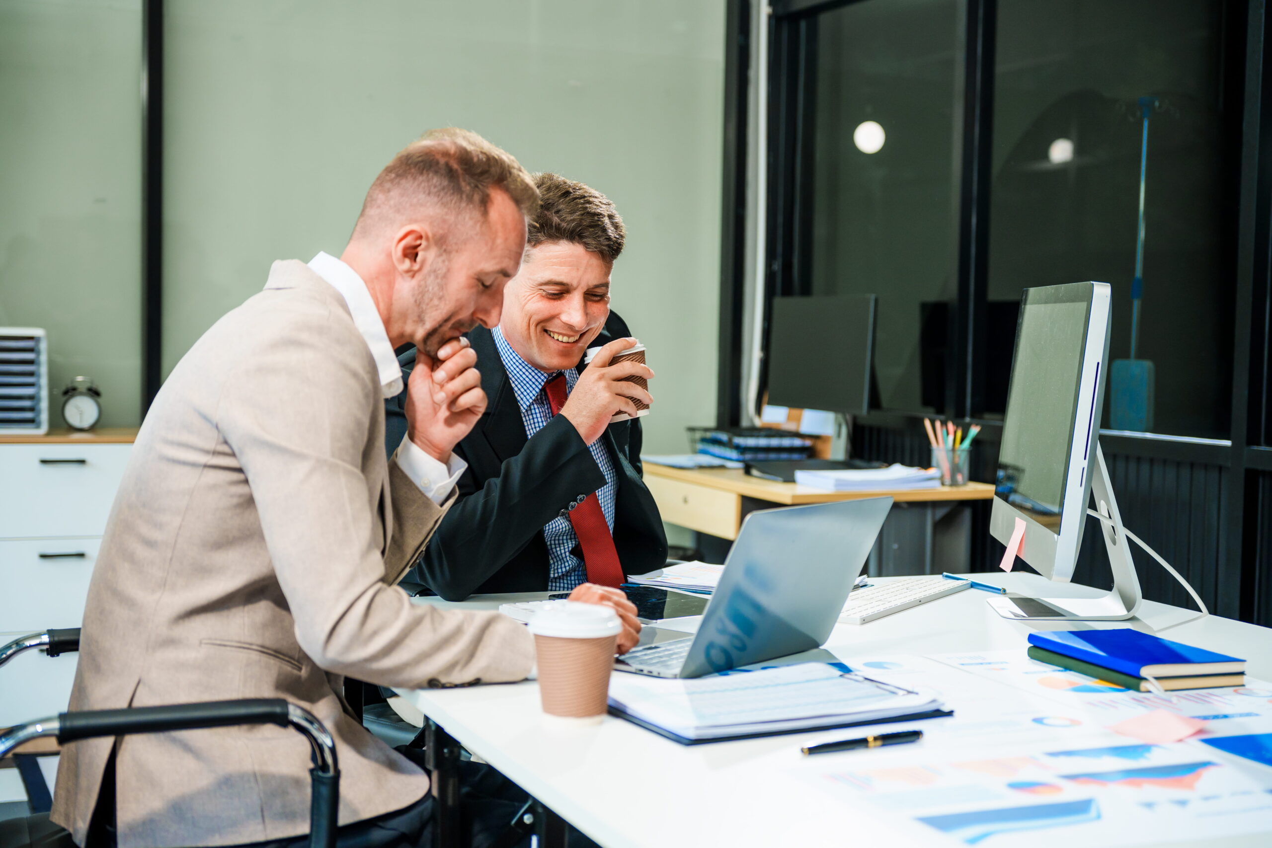 Two businessmen laughing at an office desk