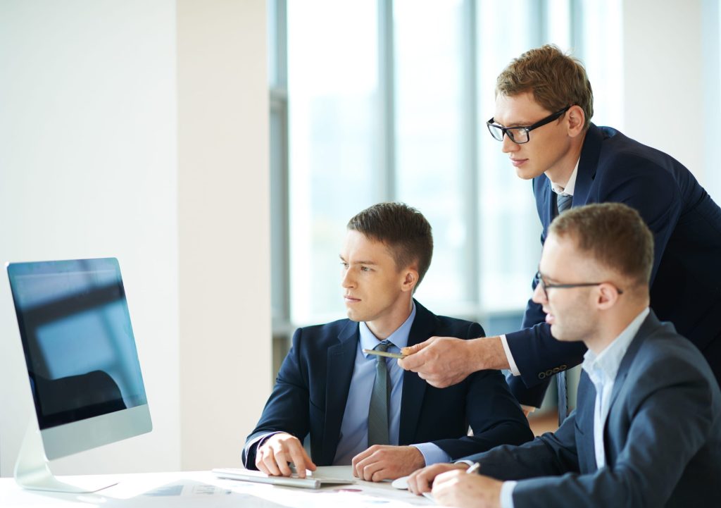 Team meeting around a computer screen in office.