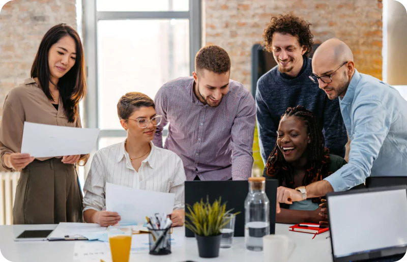 Diverse team collaborating around a laptop in office.