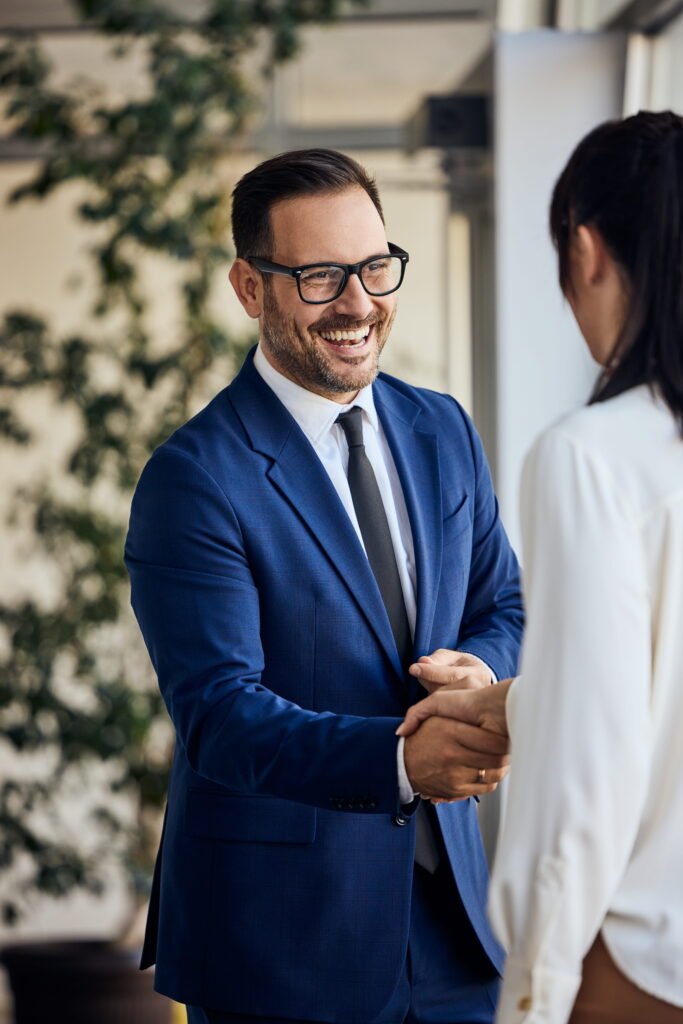 Businessman in blue suit shaking hands, smiling.