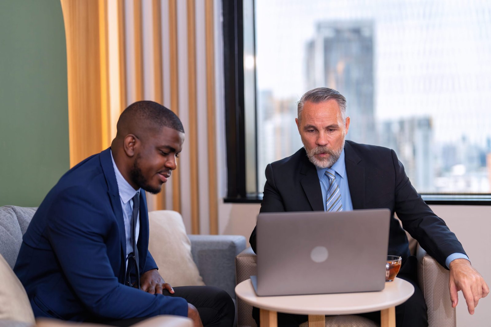 Two businessmen discussing work over a laptop.