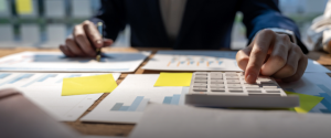 Person calculating finances with documents and calculator.