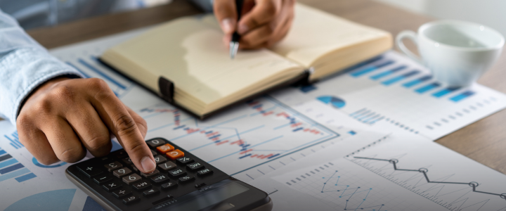 Person calculating finances with calculator and notebook.