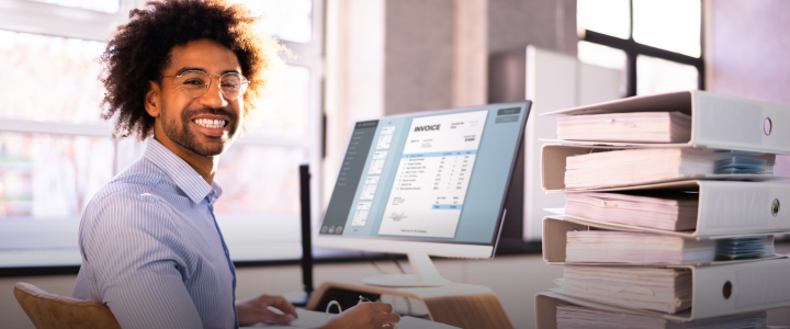 outsourced accounting man working on computer with invoices.