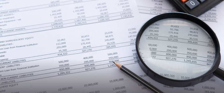outsourced accounting spreadsheet with magnifying glass and calculator.