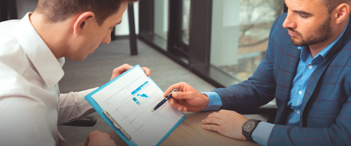 Two men discussing an outsourced accounting business report.