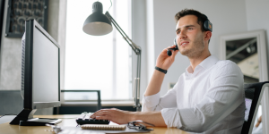 Man wearing headset working at desktop computer